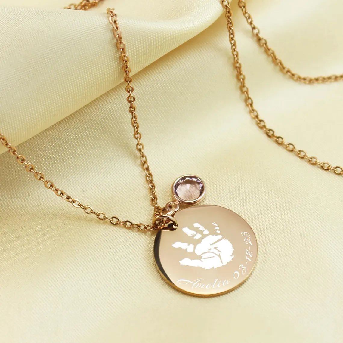 "Custom baby handprint necklace in silver—a perfect new mom gift or push present. This keepsake jewelry features an actual handprint engraving and a birthstone accent, shown styled on a person."