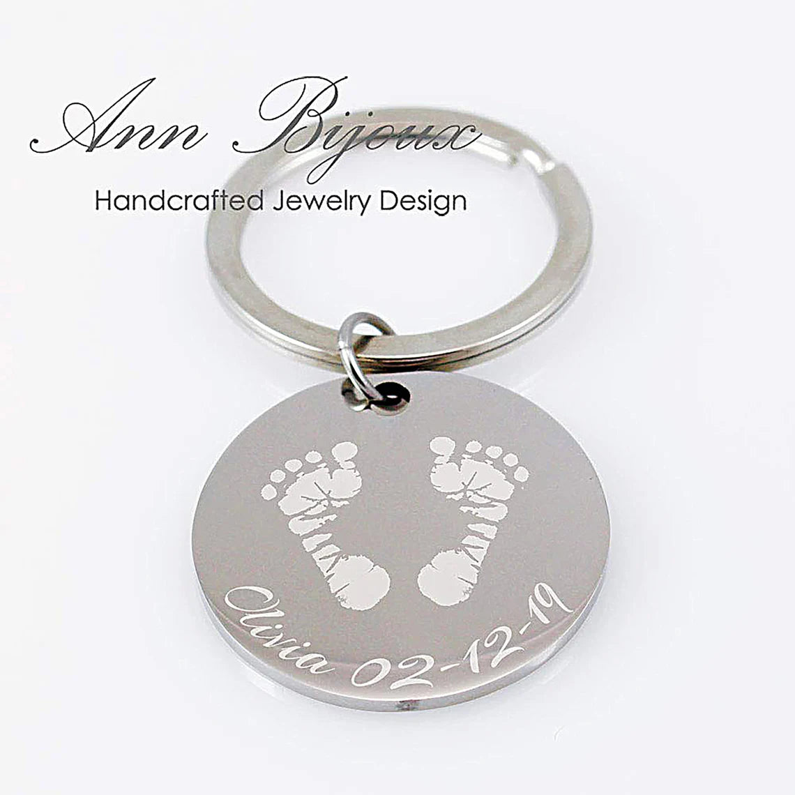 Custom footprint engraved silver keychain. Personalized baby footprint jewelry with name and birthdate detail, showcasing the transformation from an ink print to a metal engraving.