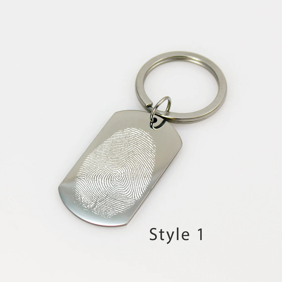 Custom silver dog tag keychain engraved with a detailed white fingerprint on a polished metal surface.