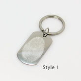 Custom silver dog tag keychain engraved with a detailed white fingerprint on a polished metal surface.