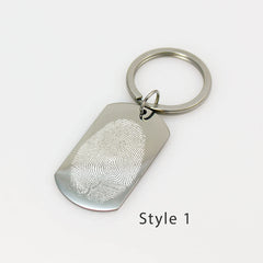 Custom silver dog tag keychain engraved with a detailed white fingerprint on a polished metal surface.