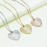Three heart-shaped fingerprint pendants on gold, silver, and rose gold chains against a white background.