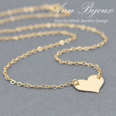 Gold heart-shaped pendant necklace on a gray background with 'Ann Bijoux' branding.