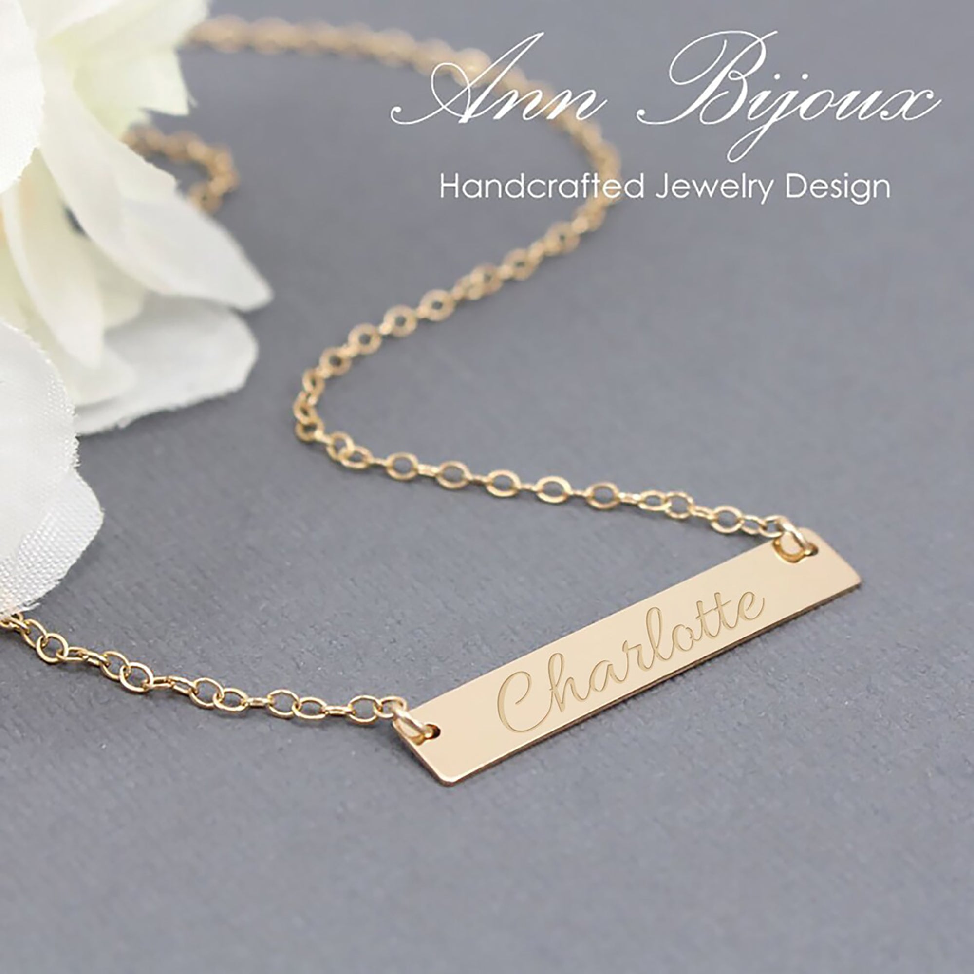 Gold necklace with engraved name on a gray background, featuring 'Ann Bijoux' branding.
