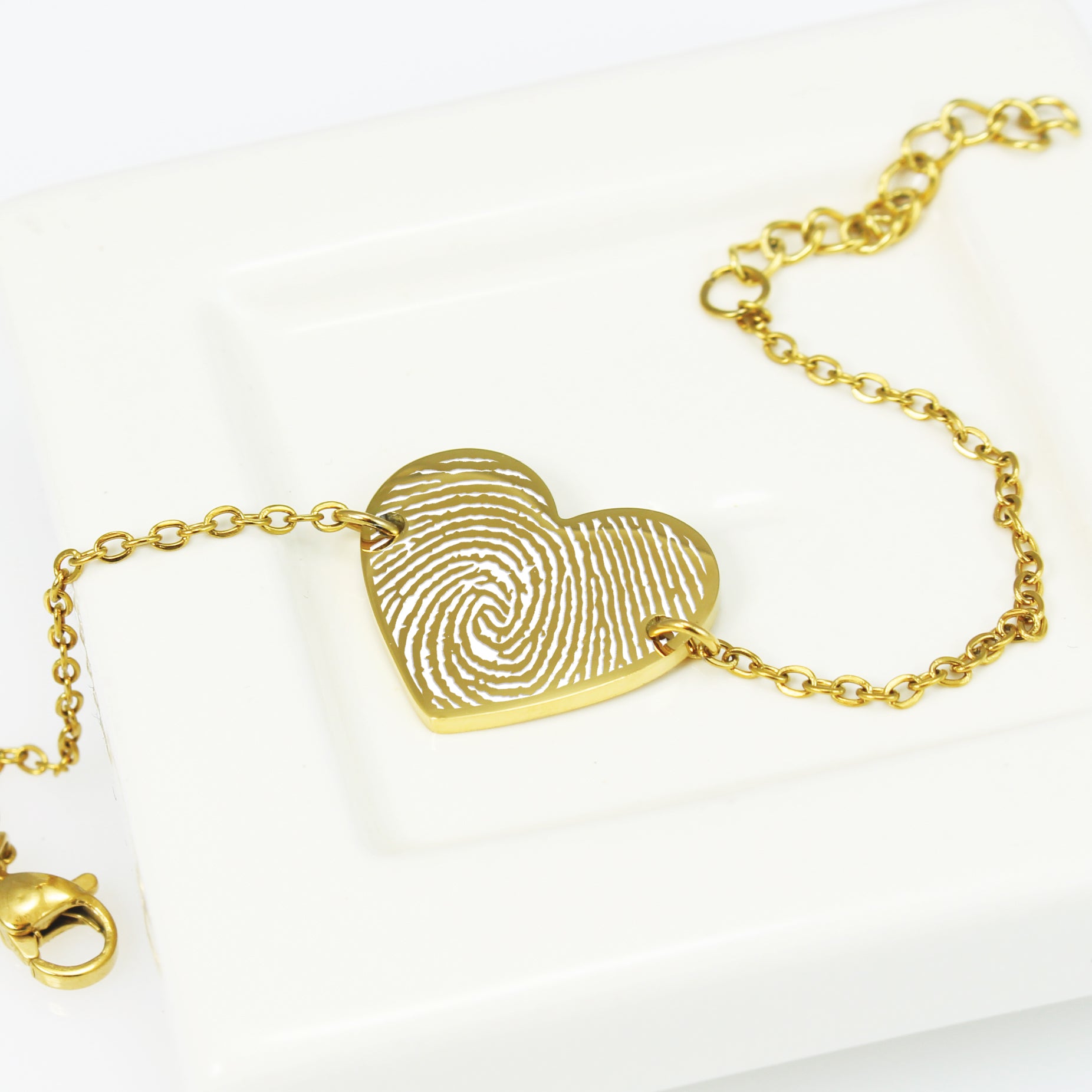 Gold fingerprint heart bracelet on a white background