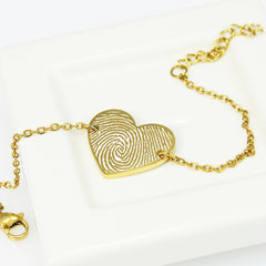 Gold fingerprint heart bracelet on a white background