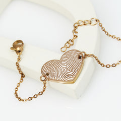 Gold fingerprint heart-shaped pendant on a chain against a white background