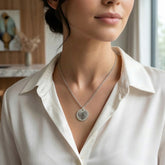 Woman wearing a silver necklace with a heart pendant in a blurred indoor setting