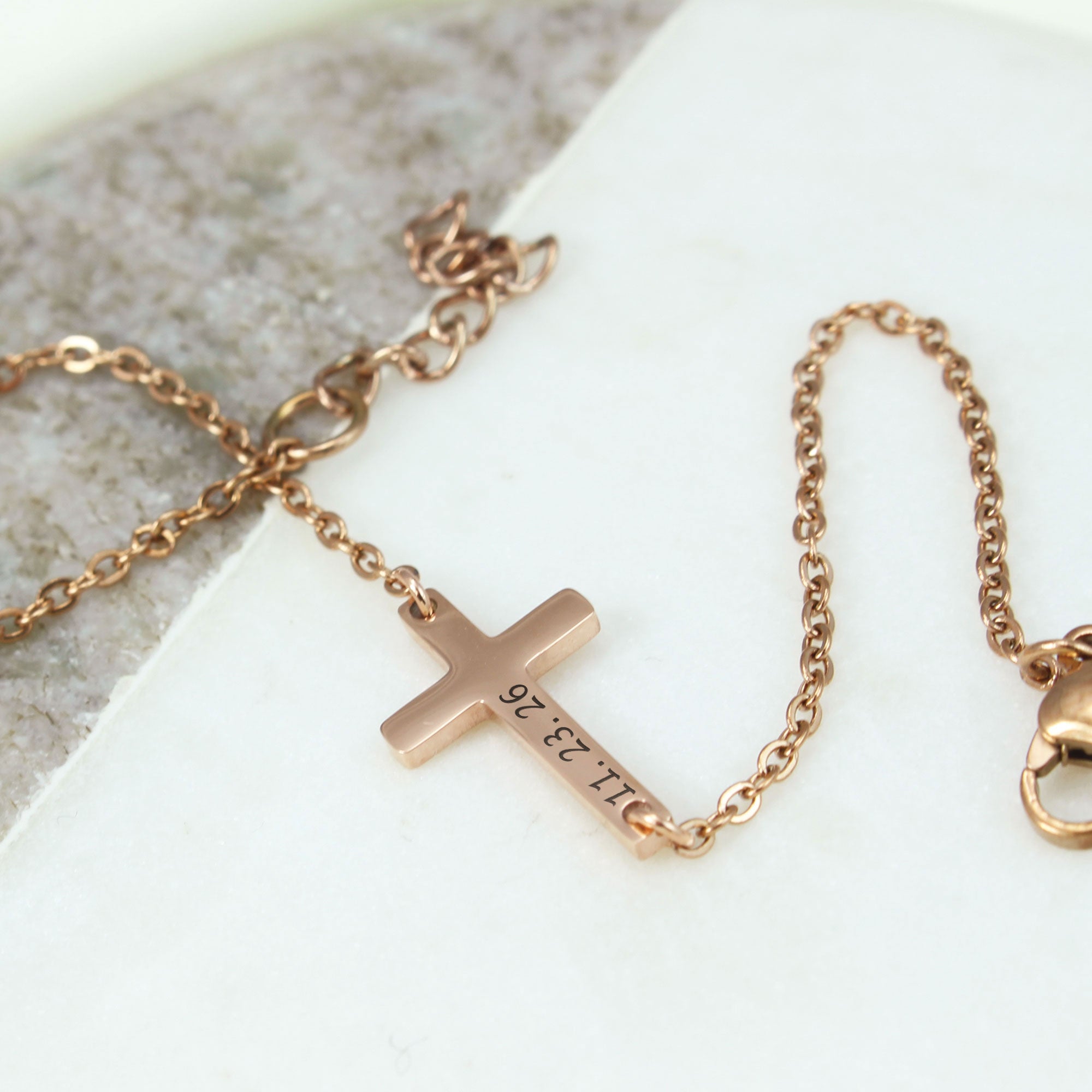 Rose gold cross necklace on a light background