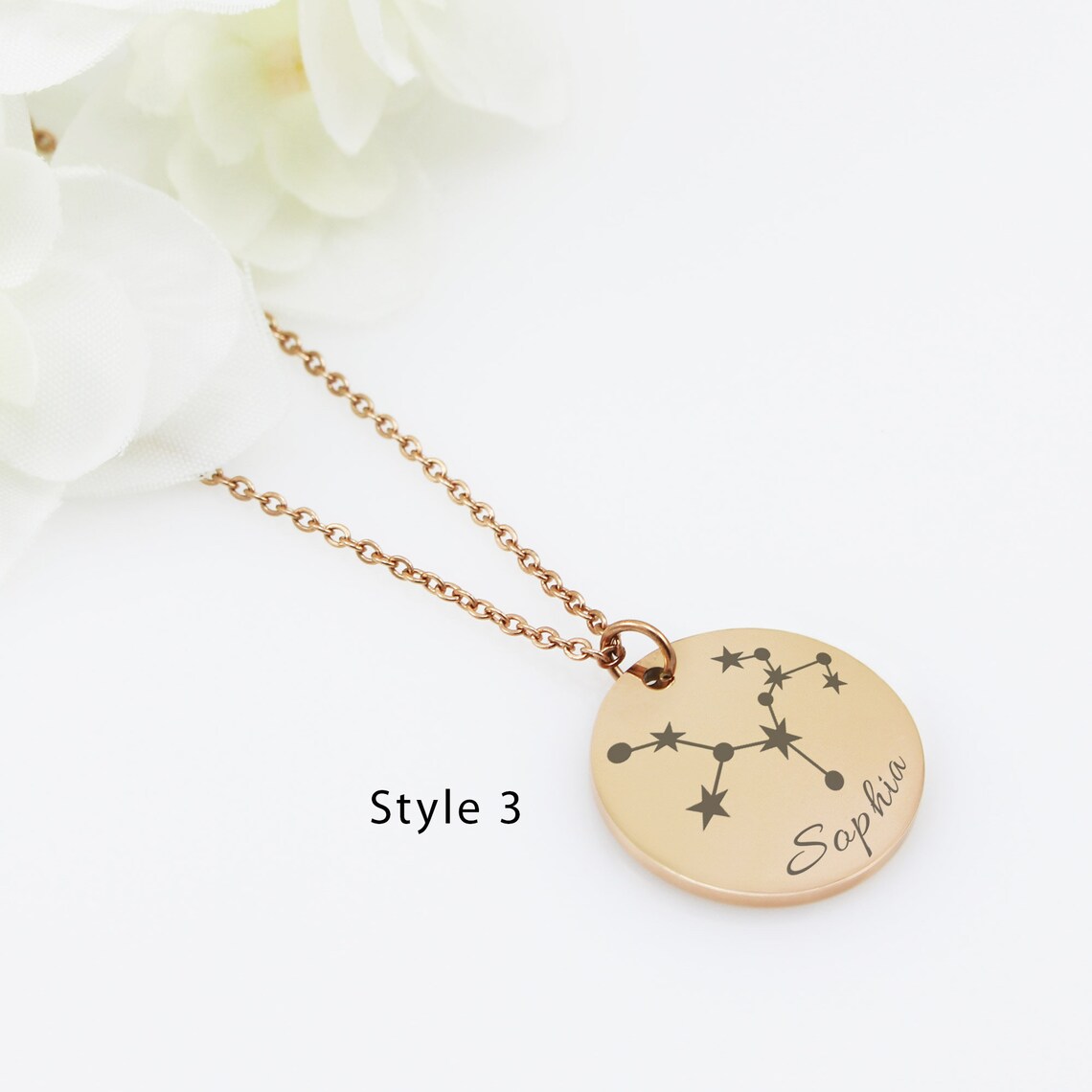 Three round personalized zodiac constellation necklaces in silver, gold, and rose gold finishes. Each disc pendant features a unique star map engraving and a custom name—Olivia, Emma, and Sophia—in elegant black script.