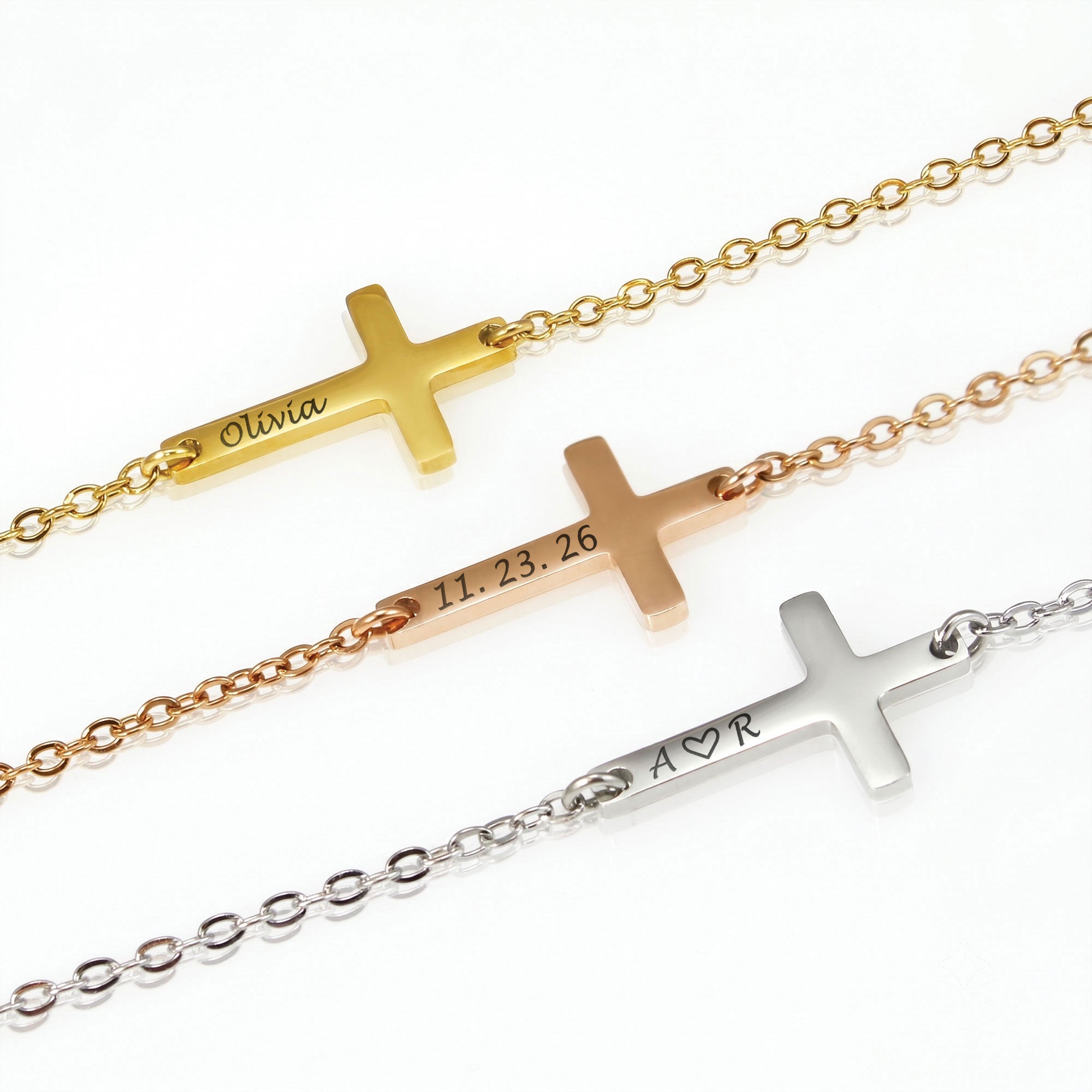 Three cross-shaped bracelets in gold, rose gold, and silver on a white background.