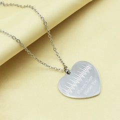 Heart-shaped silver pendant necklace on a yellow fabric background