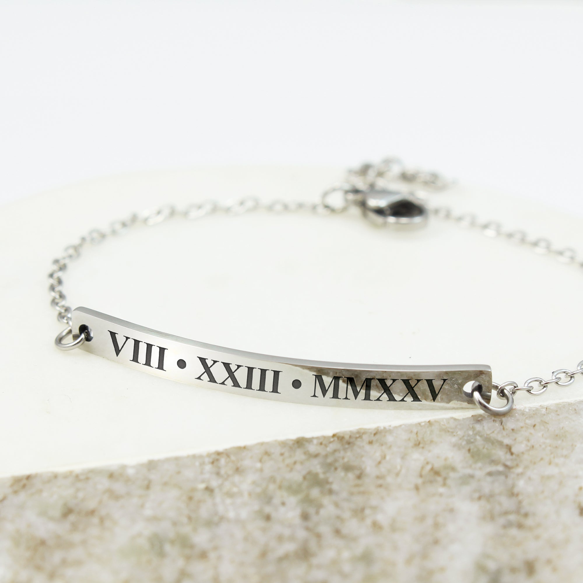 Silver bracelet with Roman numeral engraving on a stone surface