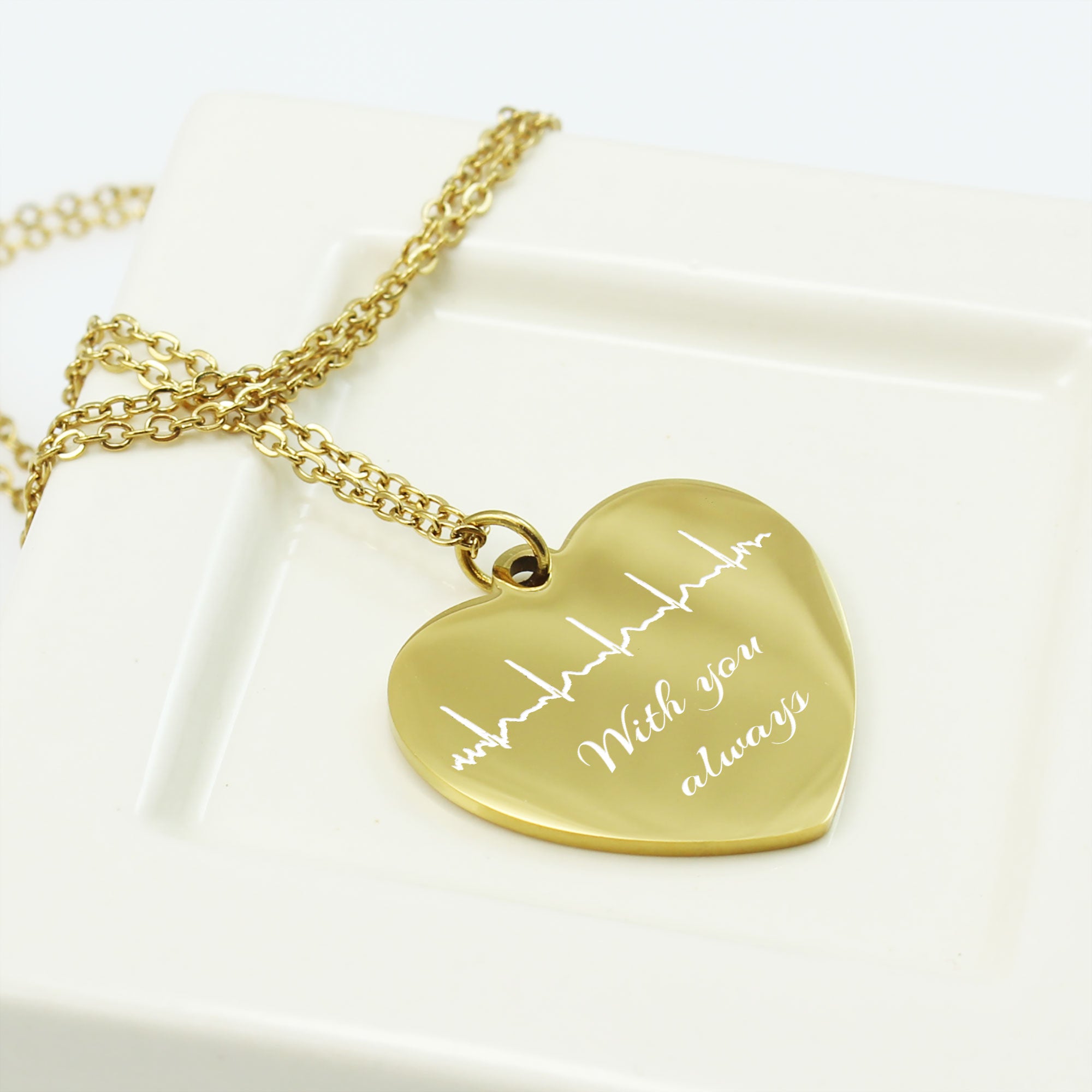 Gold heart-shaped pendant with engraved text on a white surface