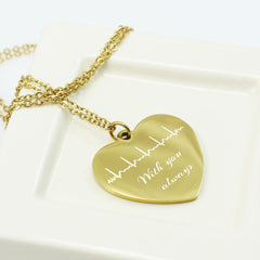 Gold heart-shaped pendant with engraved text on a white surface
