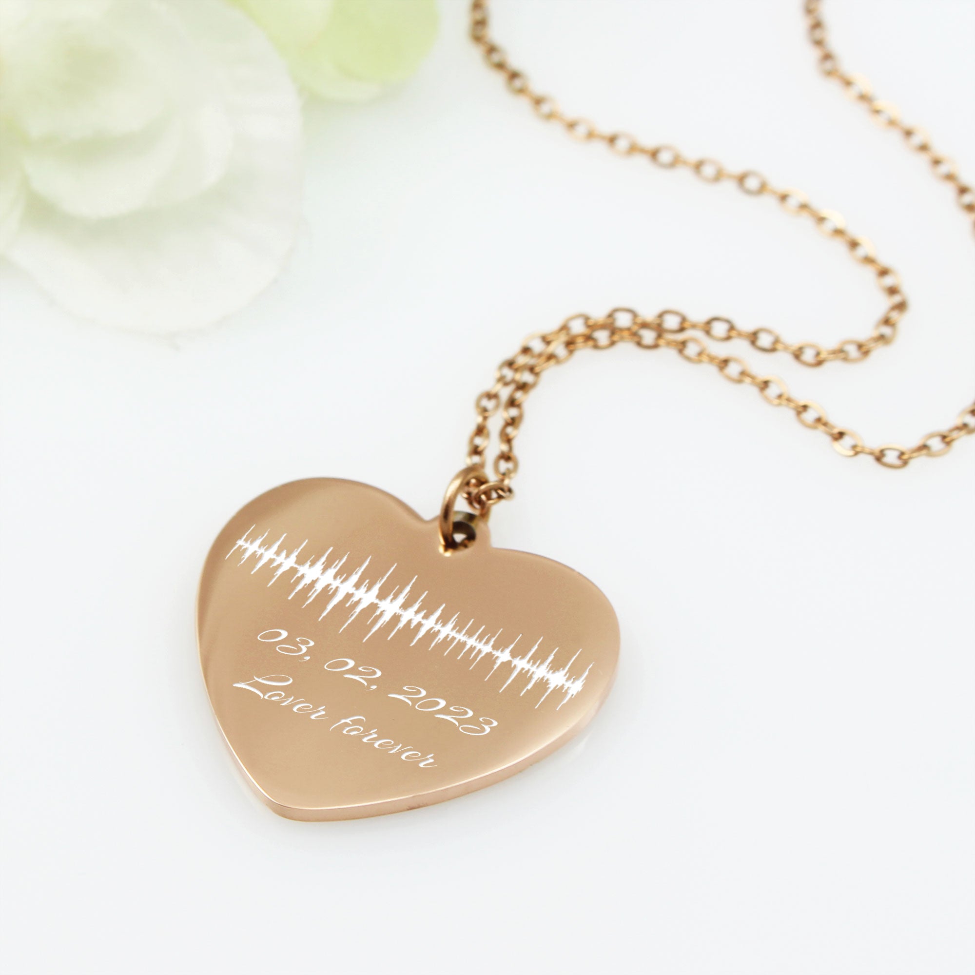 Heart-shaped rose gold necklace with engraved birthday on a white background