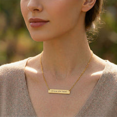 Woman wearing a gold necklace with 'I love you mom!' engraving outdoors
