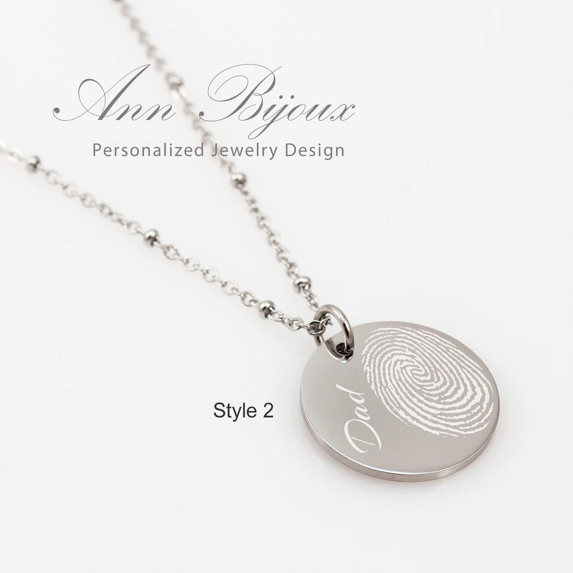 "personalized silver round disc necklace with a custom fingerprint engraving. The pendant hangs from a delicate satellite chain featuring small bead accents, shown on a person for scale."