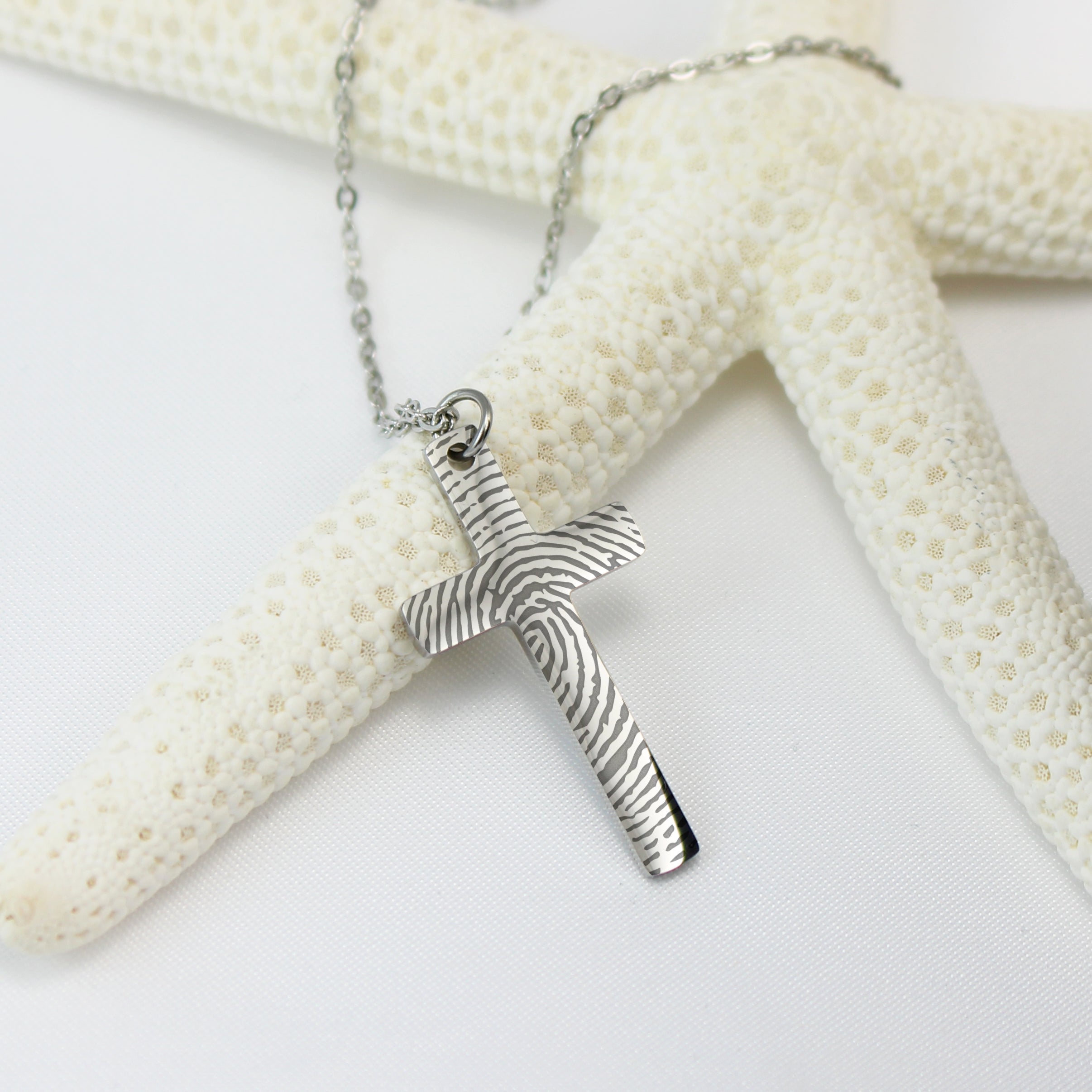 Silver necklace with a cross pendant on a white surface