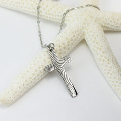 Silver necklace with a cross pendant on a white surface