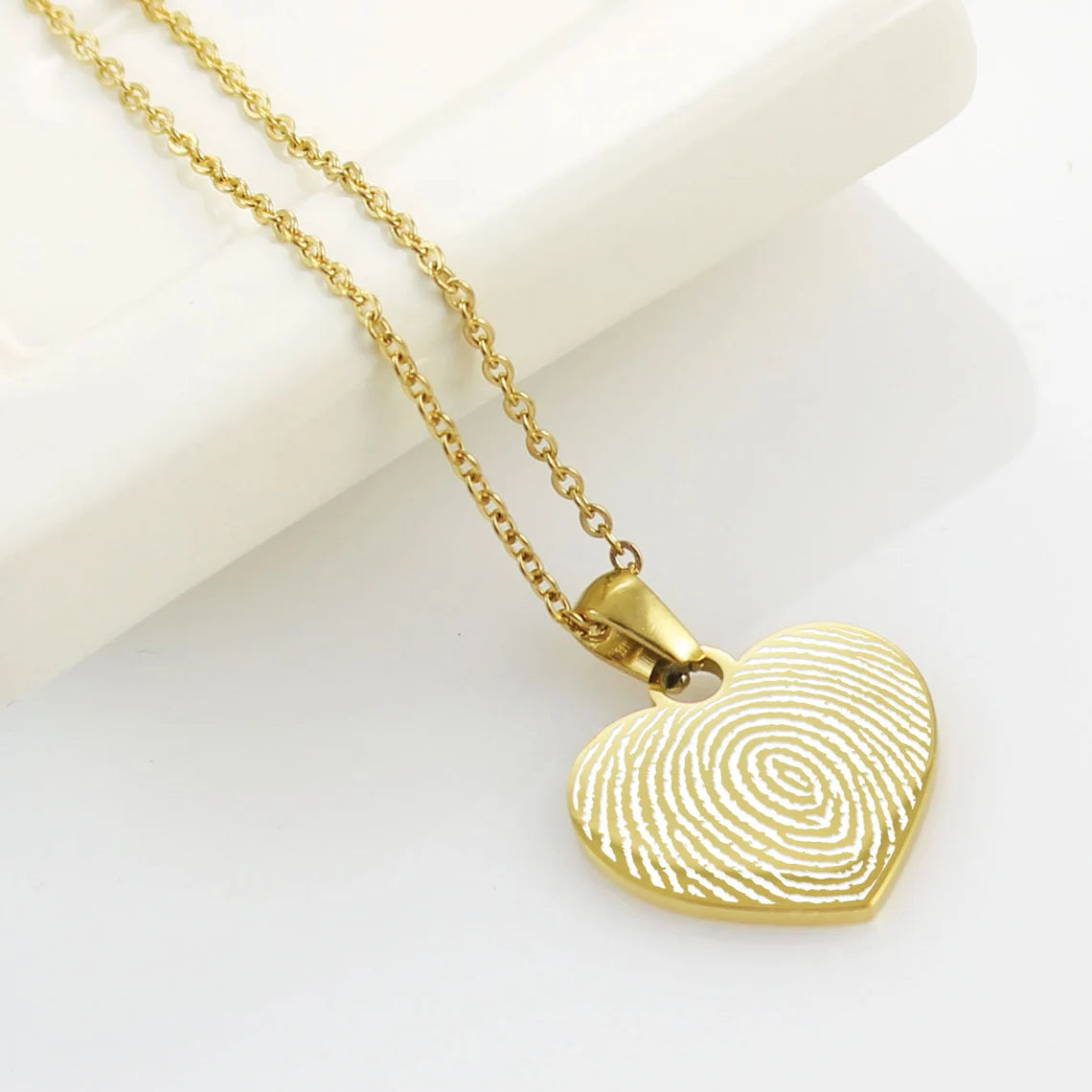 Custom fingerprint heart necklaces in three different metal colors.