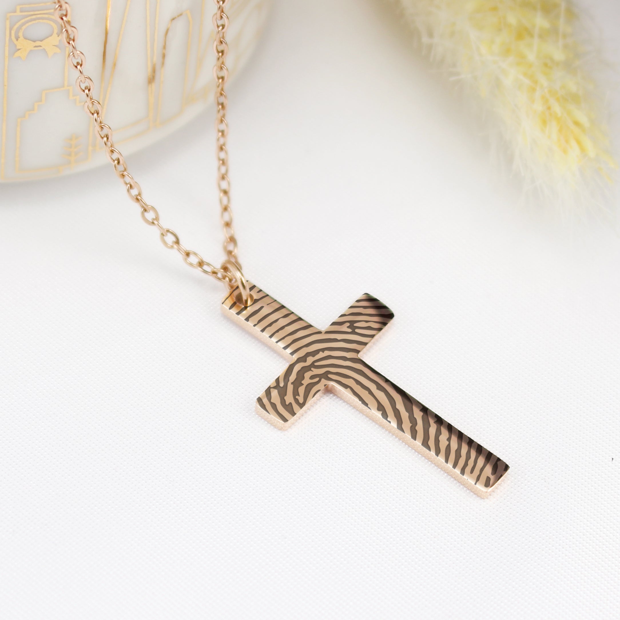Rose gold cross necklace on a white background