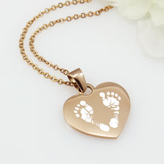 "Personalized silver heart necklace with baby footprint engraving and custom name."