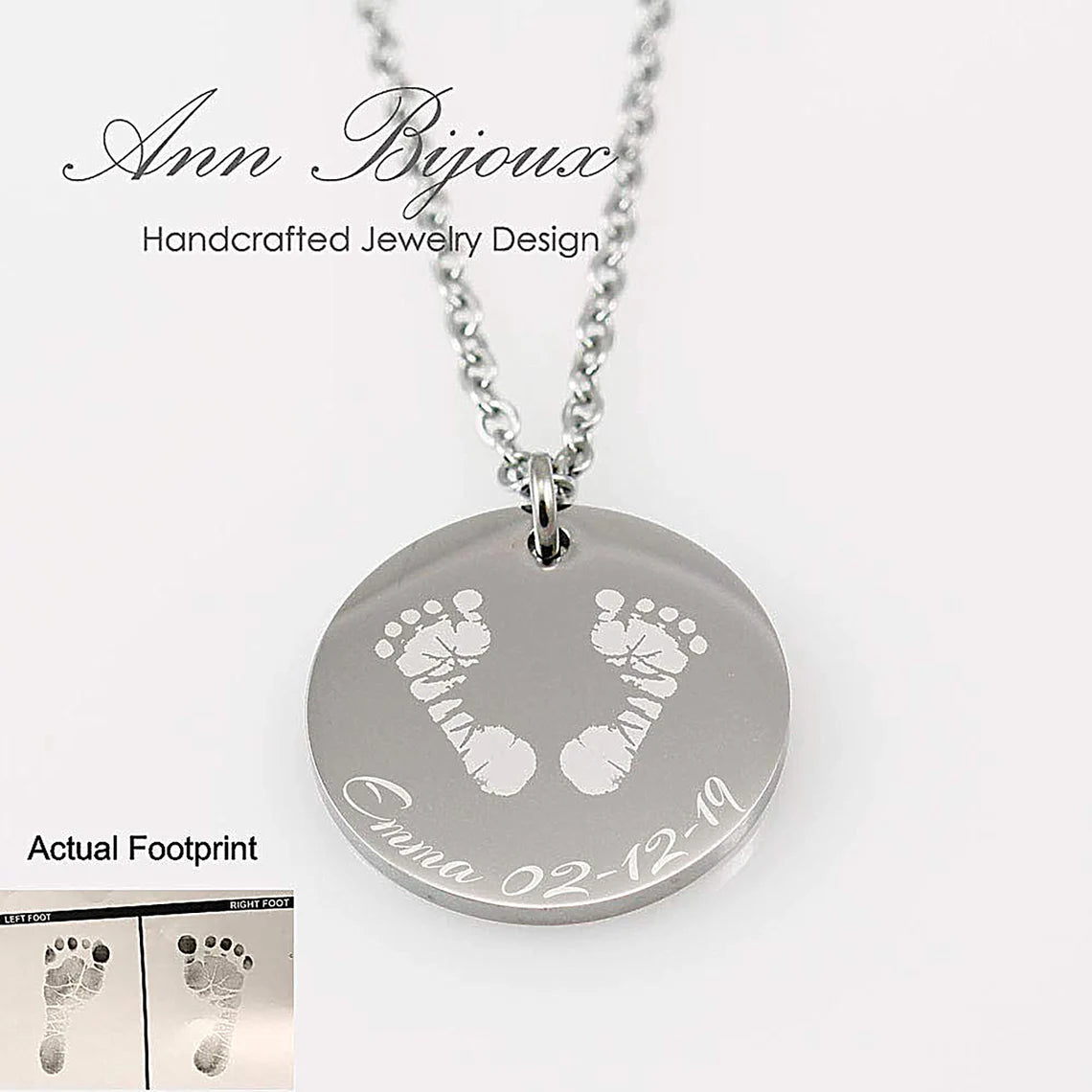 "Custom baby footprint necklace in silver. A highly detailed engraving of a newborn's actual footprints is etched onto a polished round disc pendant, personalized with the name 'Emma' and date '02.12.19'."