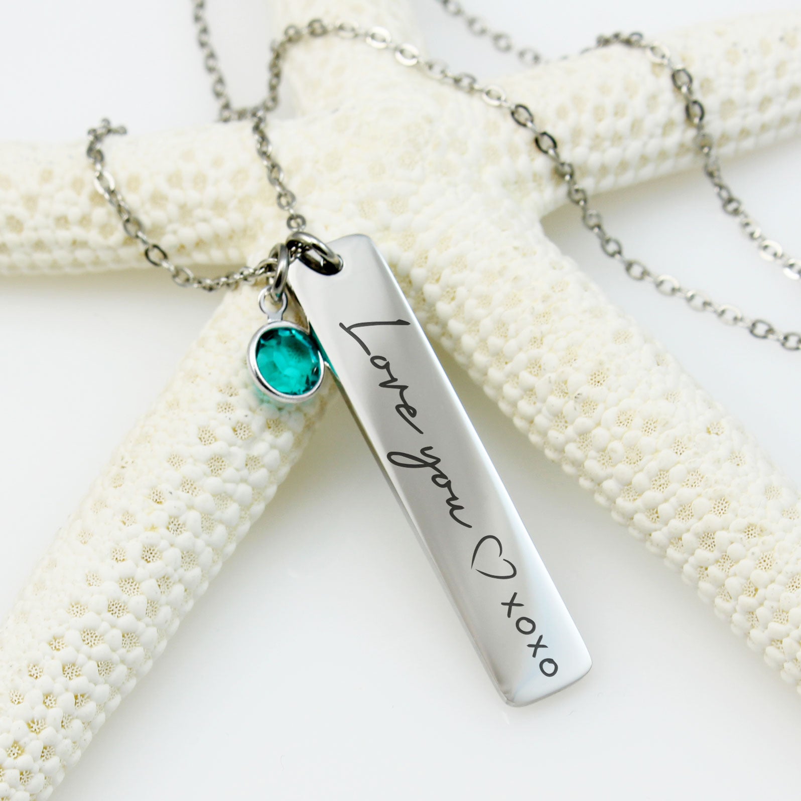 A single corresponding round birthstone charm (blue, red, and purple) hangs from the delicate chain above each pendant."
