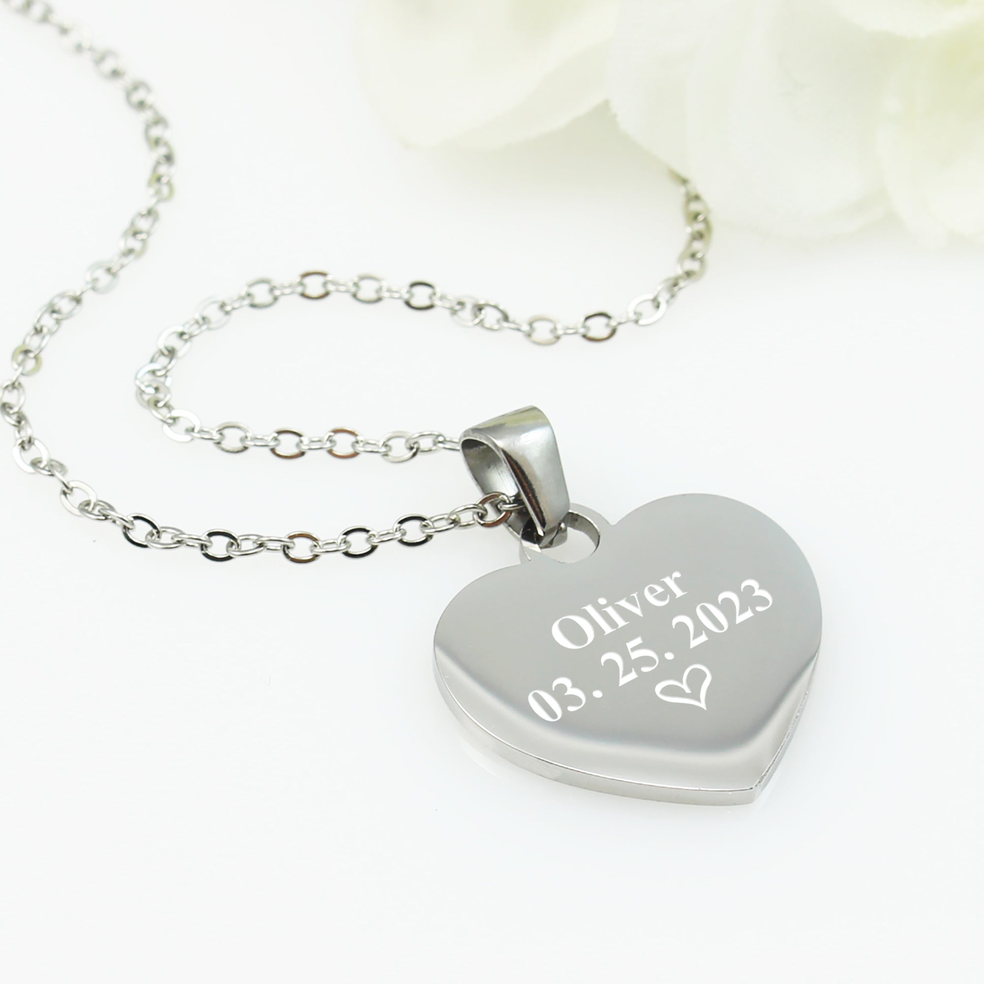 Heart-shaped silver pendant with engraved text on a white background