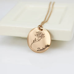 A stainless steel necklace with a round pendant featuring a laser engraved birth flower and the name 'Zabella' on it.