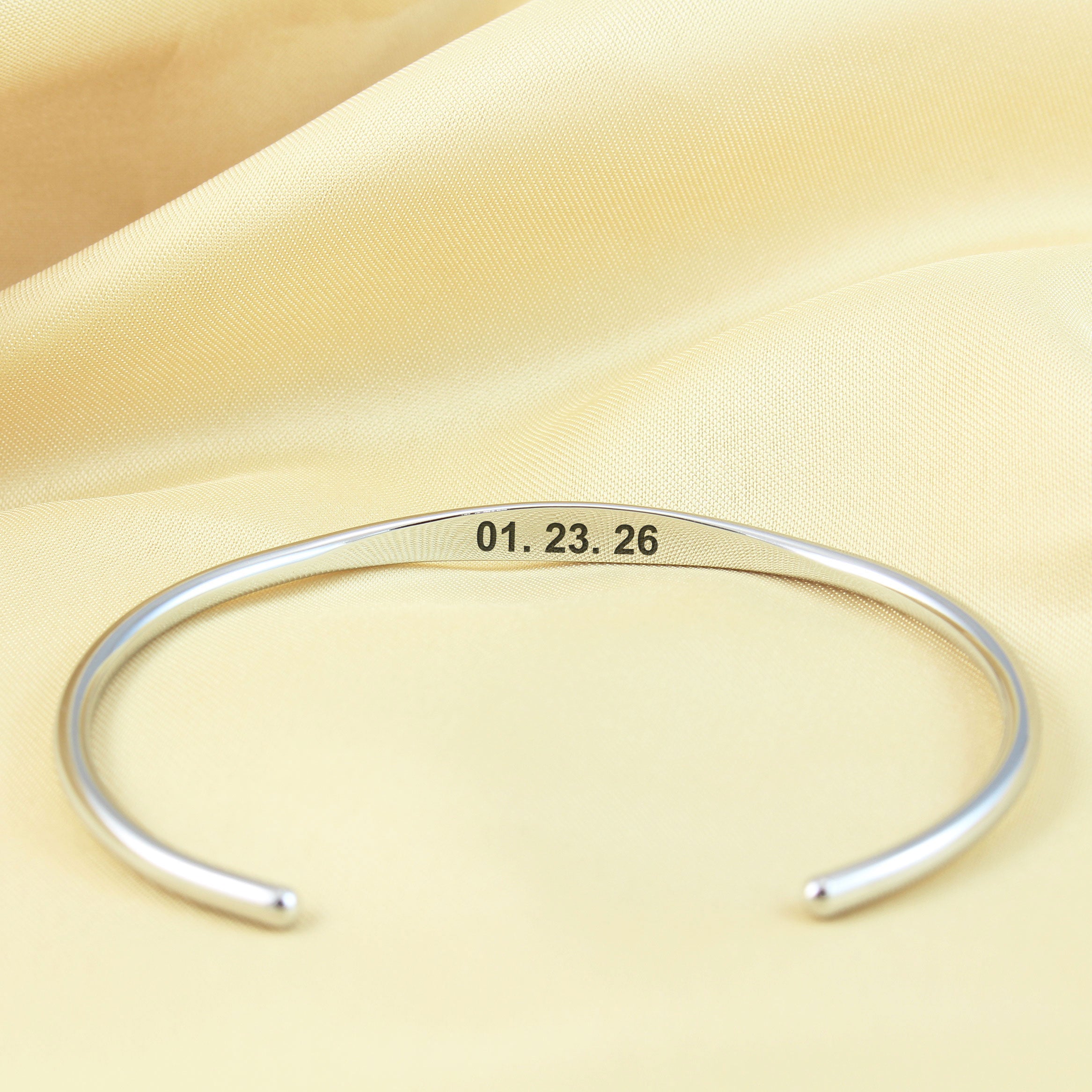 A polished silver open cuff bracelet engraved with the date '01.23.