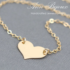 Gold heart-shaped pendant necklace on a gray background with 'Ann Bijoux' branding.