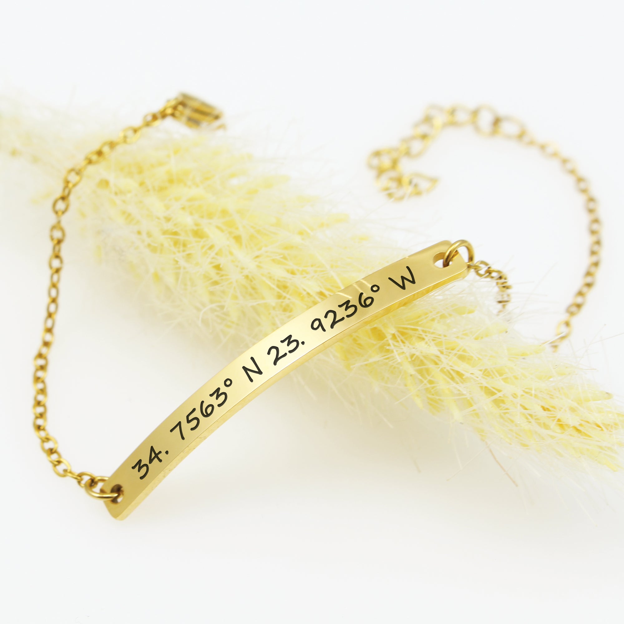 Gold bracelet with engraved coordinates on a white background