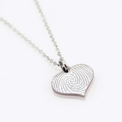 "Stainless steel silver heart-shaped pendant necklace featuring a custom deep-etched fingerprint engraving. The unique swirl of the fingerprint is prominently displayed on the polished heart charm."