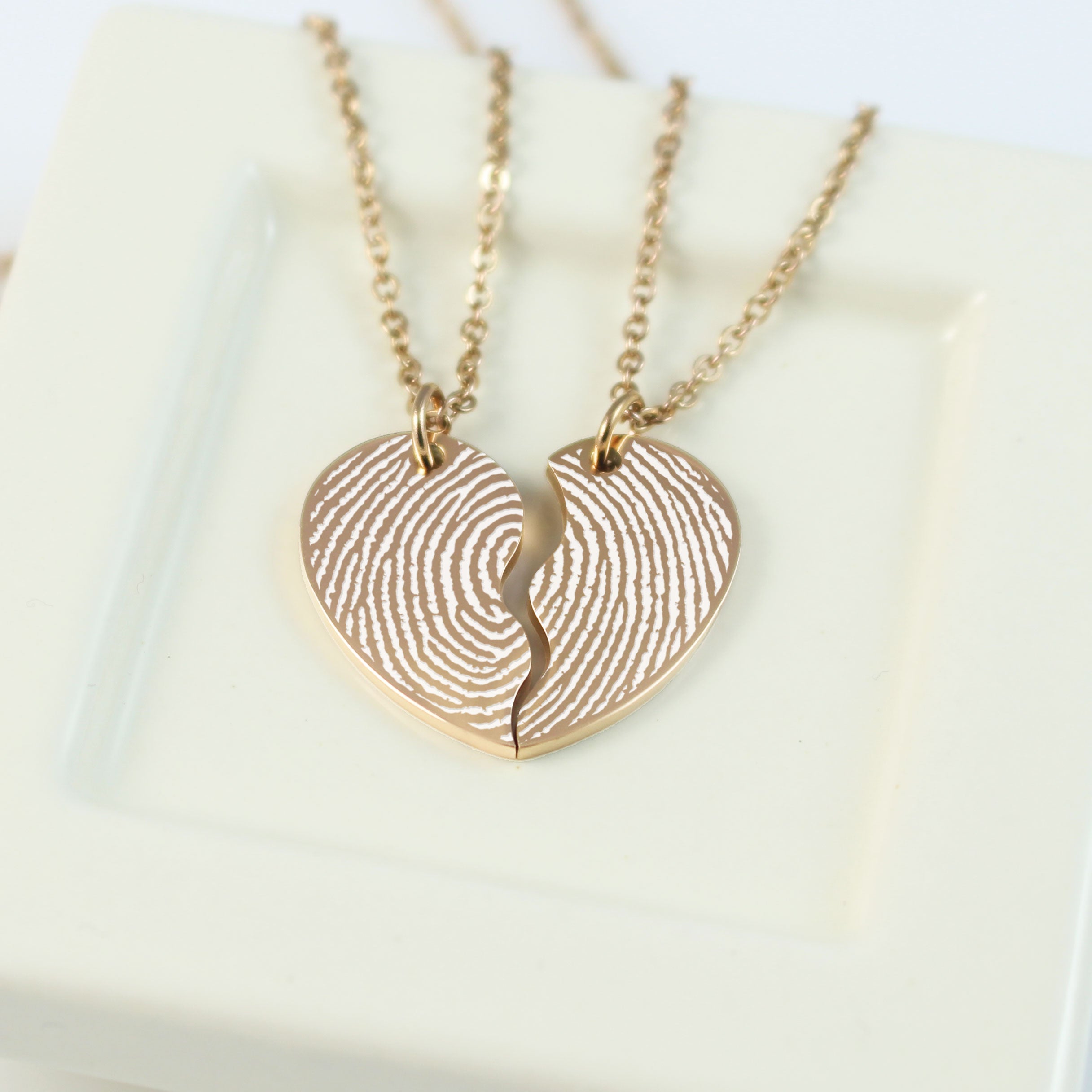 Gold fingerprint heart necklace on a white background