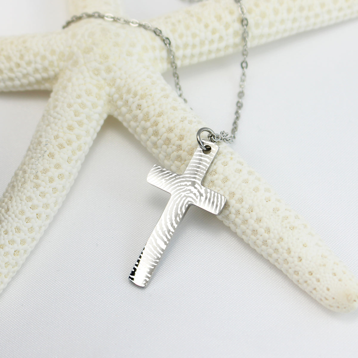 Silver cross pendant necklace on a starfish with a white background