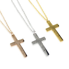 Three cross necklaces in gold, silver, and rose gold on a white background