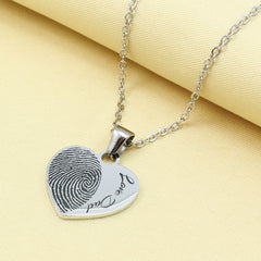 Heart-shaped fingerprint pendant necklace on a yellow fabric background