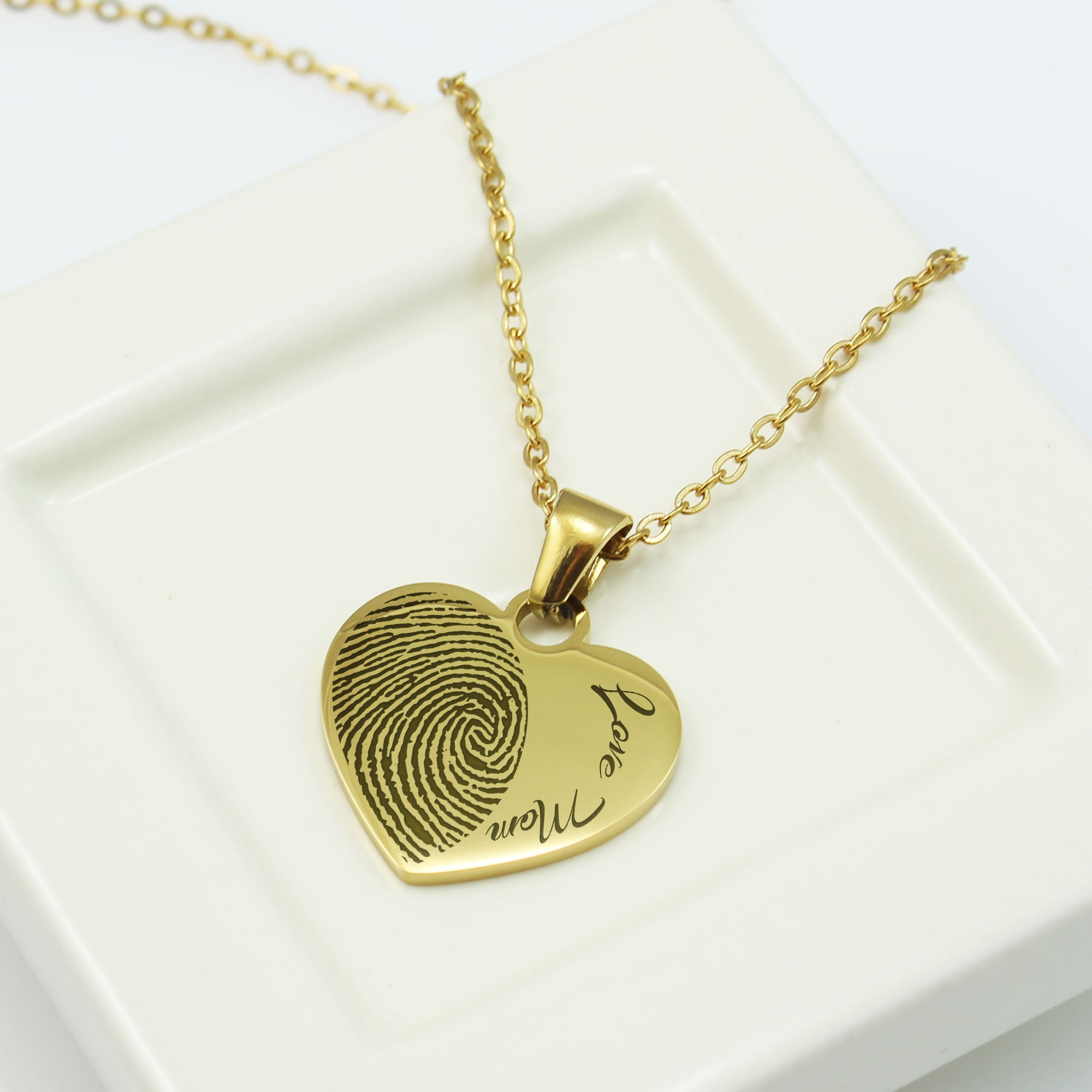 Gold fingerprint heart pendant necklace on a white box background