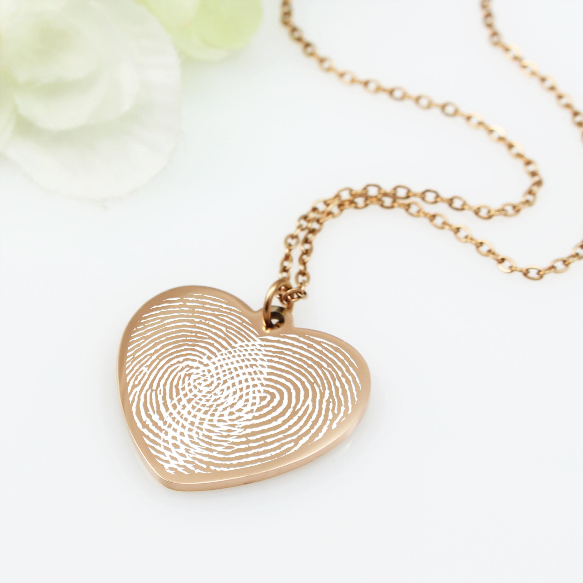 Gold fingerprint heart necklace on a white background