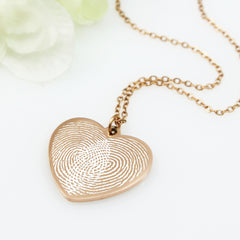 Gold fingerprint heart necklace on a white background