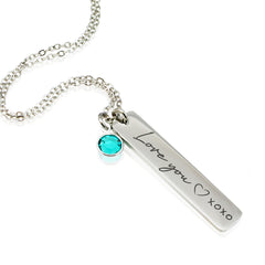 "Custom silver vertical bar necklaces for families. Each bar is engraved with a personalized name—like Mom, Anna, and Isabella—in a elegant script font. A single corresponding round birthstone charm (blue, red, and purple) hangs from the delicate chain above each pendant."