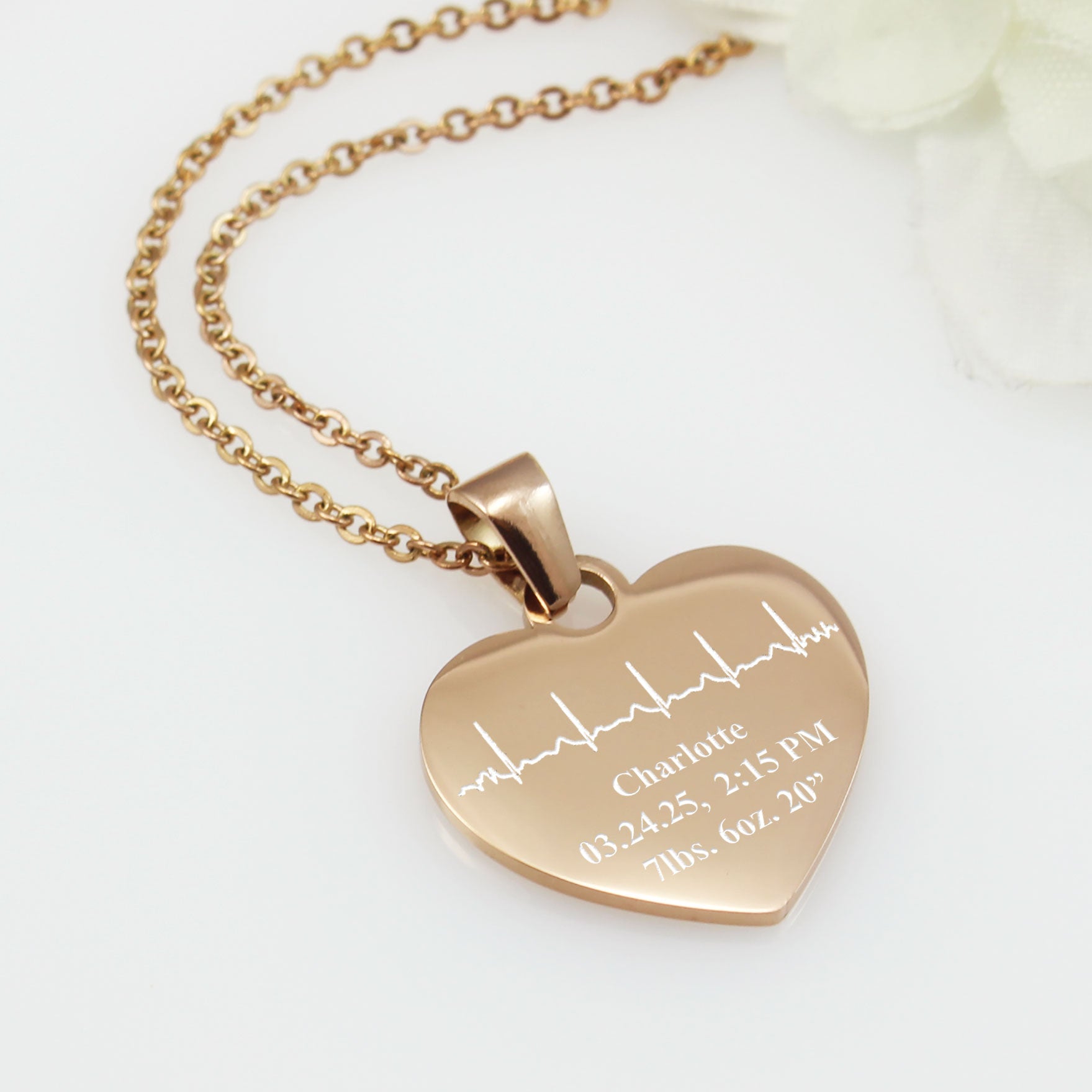 Rose gold heart-shaped necklace with engraved details on a white background