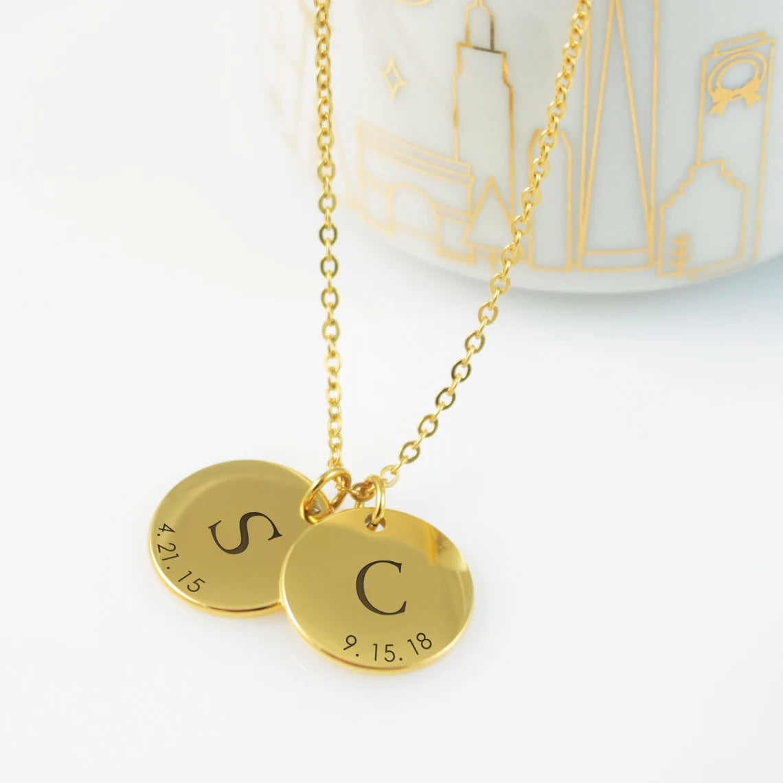 Custom engraved disc necklaces with initials and dates in gold finishes.