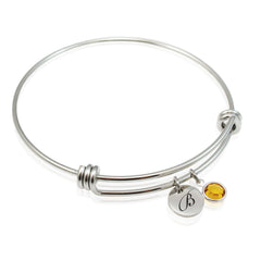 An adjustable stainless steel bracelet with a customized engraved initial and a Swarovski birthstone bead.