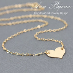 Gold heart-shaped pendant necklace on a gray background with 'Ann Bijoux' branding.