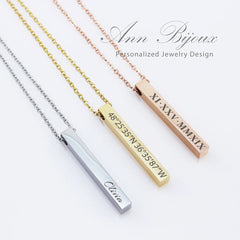 Three vertical 3D bar necklaces in silver, gold, and rose gold finishes. The silver bar is engraved with the name 'Olivia,' the gold bar features geographic coordinates, and the rose gold bar shows a date in Roman numerals.