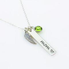 A sterling silver bar necklace with a wing charm and a green Swarovski crystal birthstone, engraved with the word 'Mom' and a heart symbol.