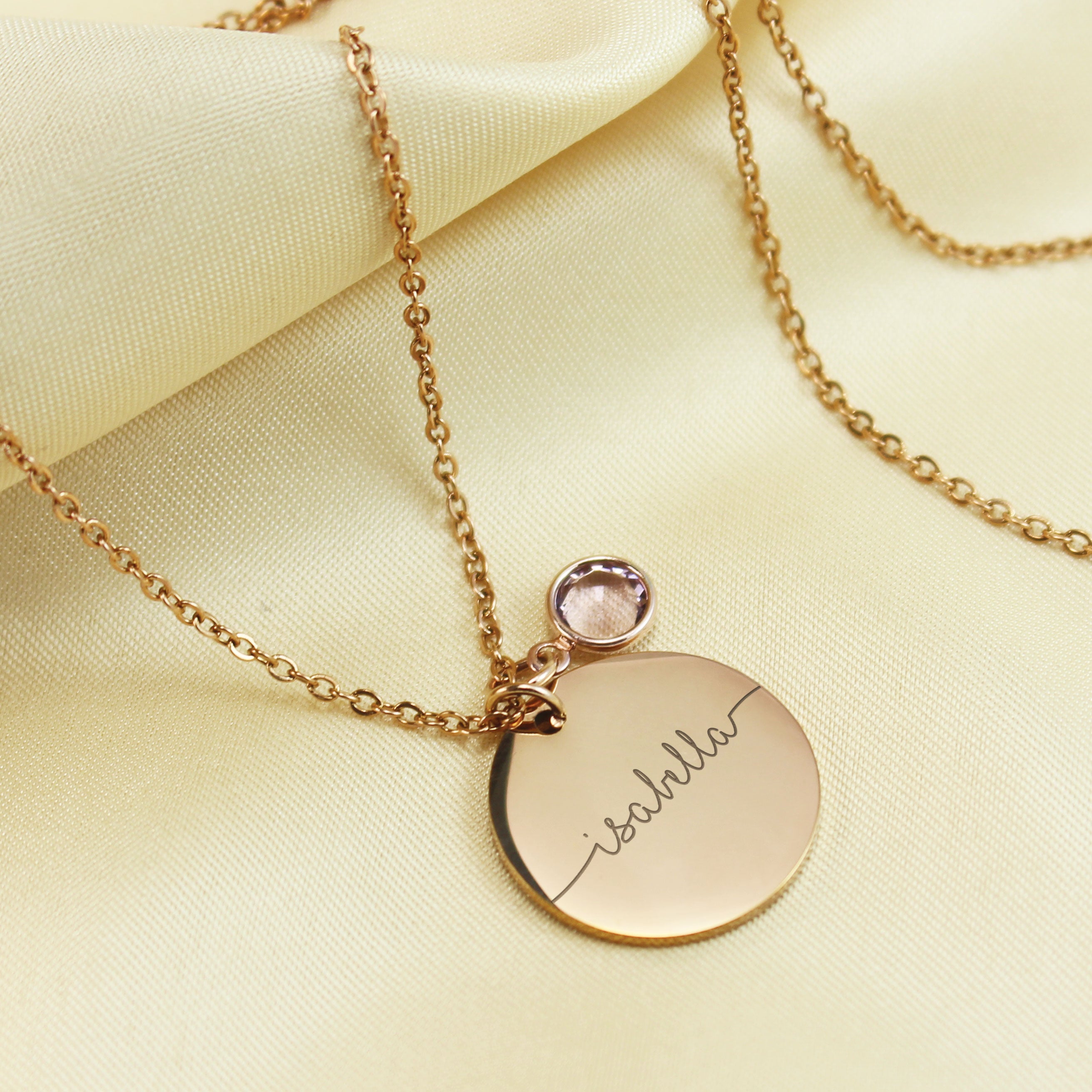 "Three personalized disc necklaces in rose gold finishes, each featuring a custom script name engraving Isabella paired with colorful round birthstone charms."